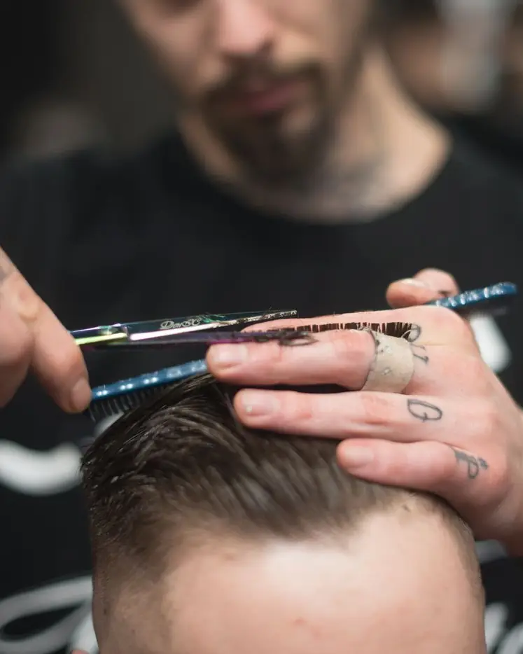 Tijera y peine sobre el cabello, a mano
